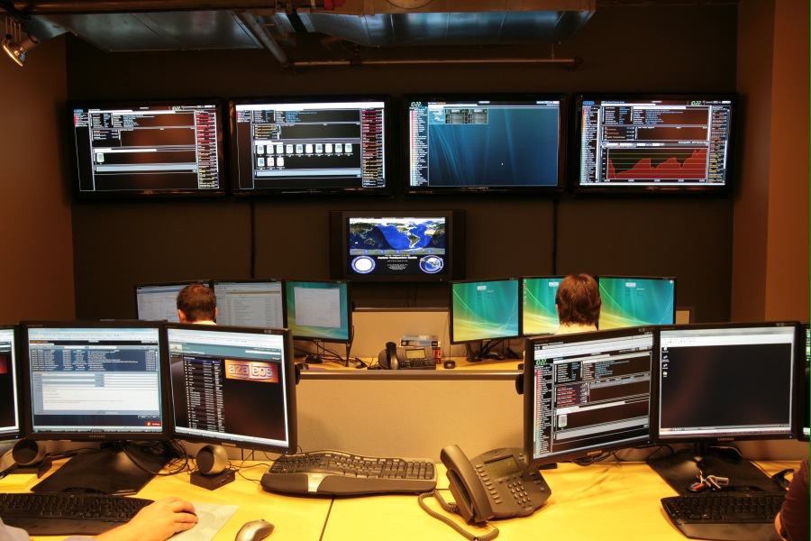 Network Operations Center with multiple monitors displaying server performance data