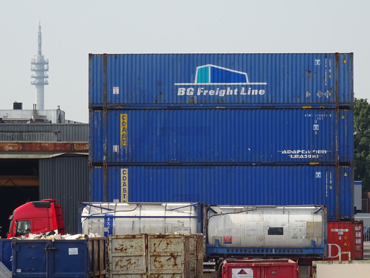 Stacked shipping containers at a port, representing software containerization and the complexity of orchestration