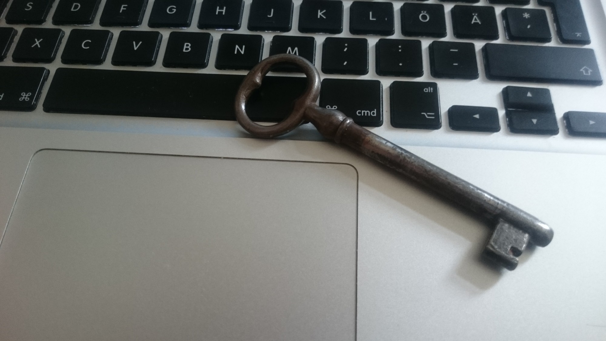 Old key sitting on a laptop keyboard, representing security and access control