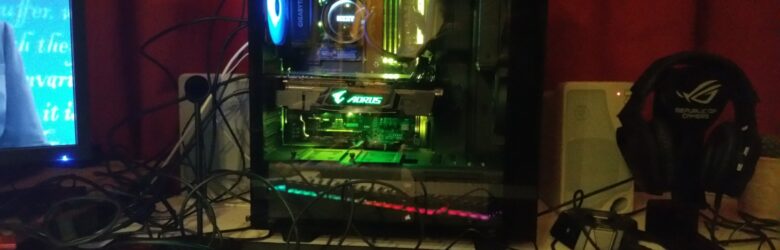 A gaming PC setup with RGB lighting, monitor, keyboard, and headset
