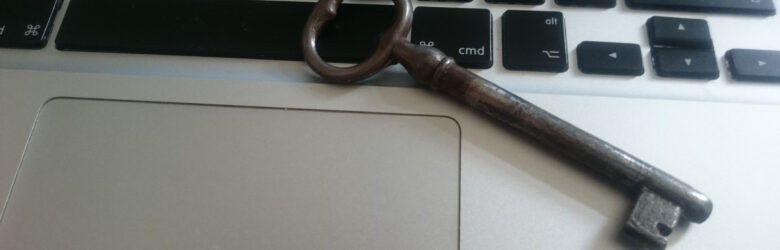 An old-fashioned key resting on a laptop keyboard, representing digital security and access control