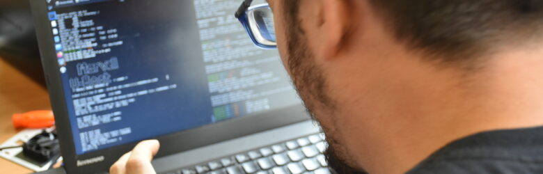 A person typing on a Linux laptop with a hacker aesthetic