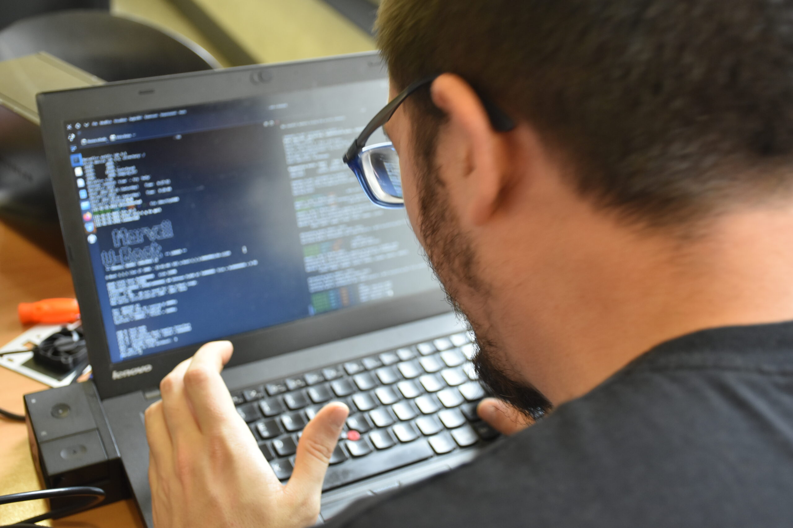 A person typing on a Linux laptop with a hacker aesthetic