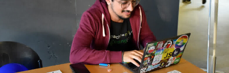 Developer typing code on a Linux laptop covered in stickers, representing cybersecurity and software supply chain security