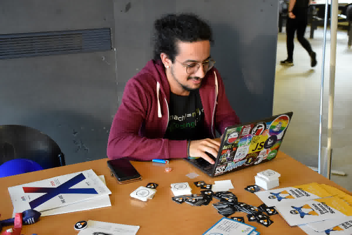 Developer typing code on a Linux laptop covered in stickers
