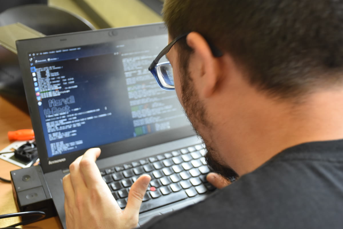 A person typing on a laptop computer with programming stickers at a technology workshop