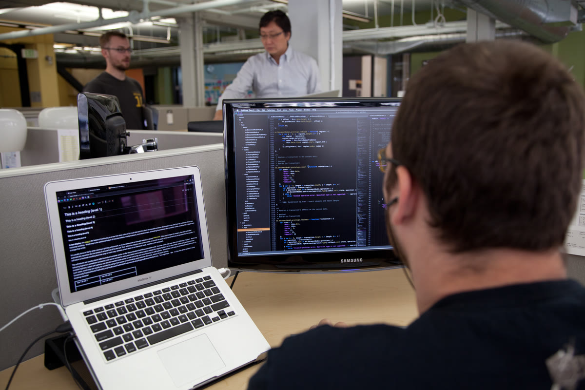 A person coding on a computer monitor in a modern workspace