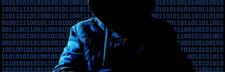 A cliche hacker in a hoodie silhouette against binary code representing cybersecurity and coding