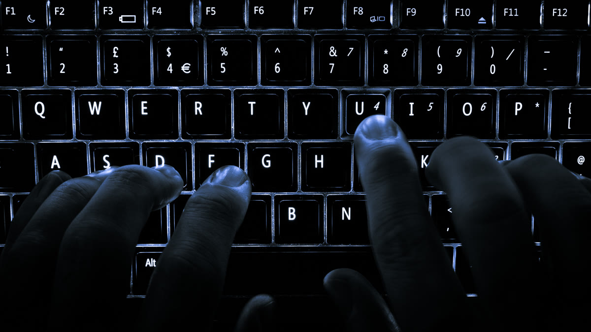 A backlit laptop keyboard showing hands on the home row keys, symbolizing developer typing