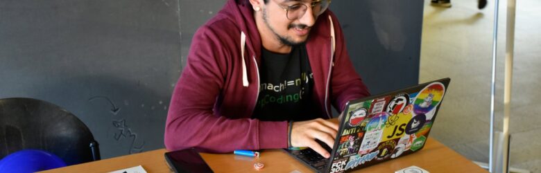 Hacker typing on a Linux laptop covered in stickers