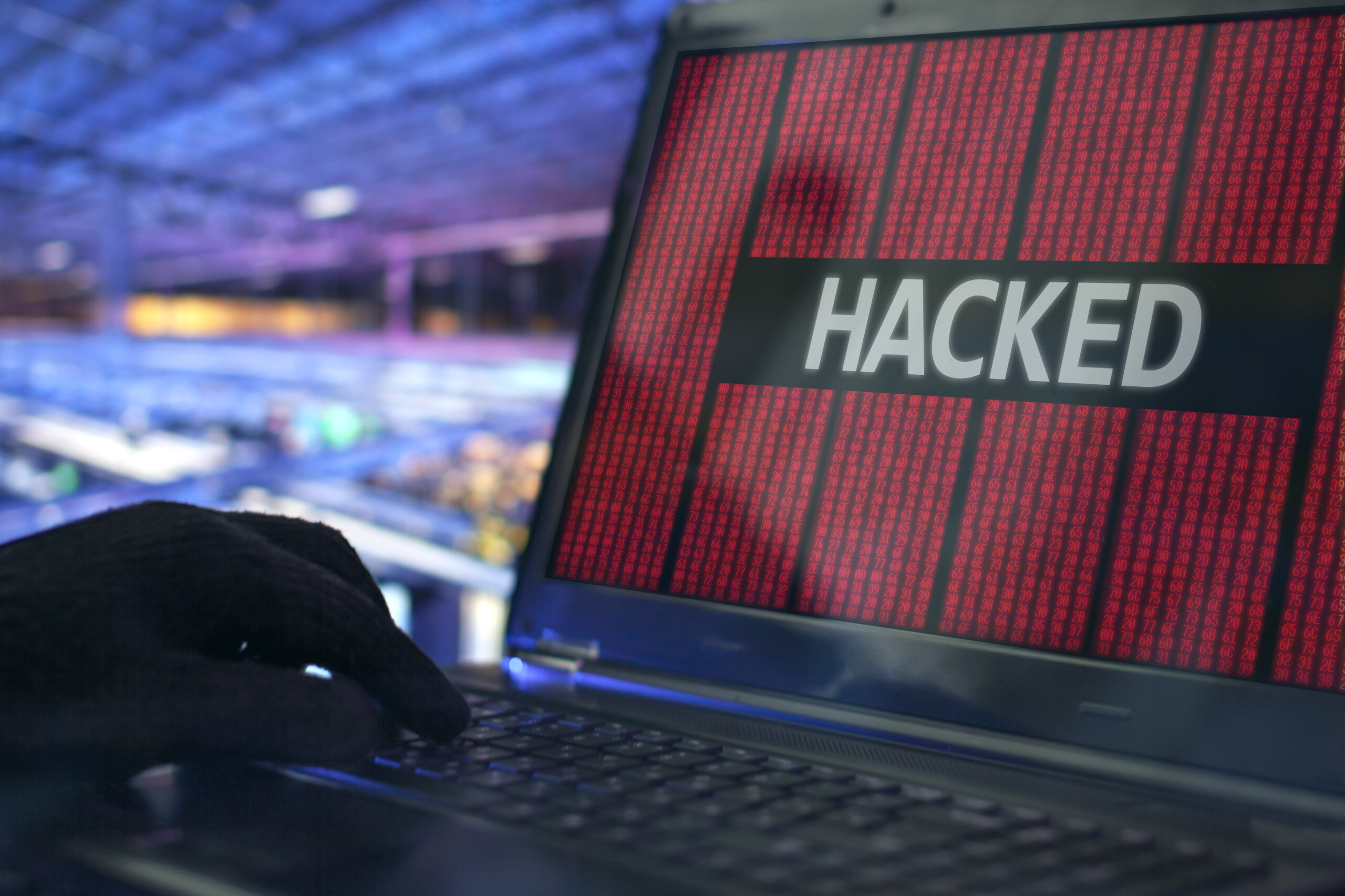 Close-up of a laptop keyboard with a person typing in dim lighting, representing cybersecurity and hacking