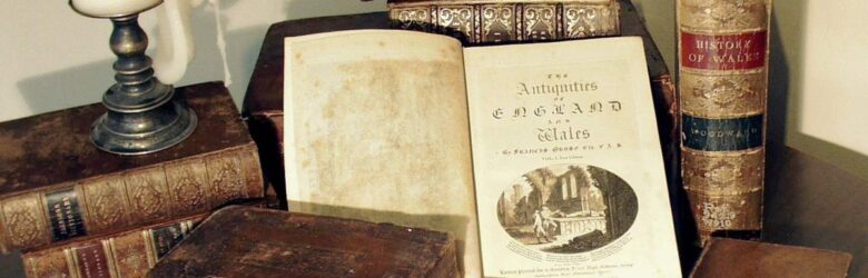 Antique books stacked with a candle, representing the rare physical books used for AI training data