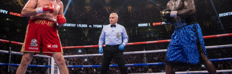 Two heavyweight boxers in the ring under bright arena lights