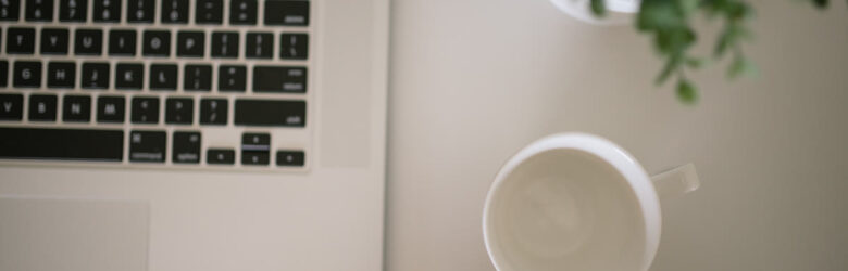 A clean desk with a laptop, a coffee cup, and a small plant — a developer workspace
