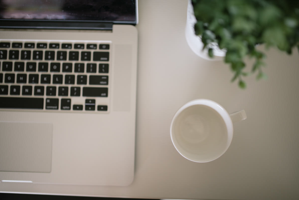 A clean desk with a laptop, a coffee cup, and a small plant - a developer workspace
