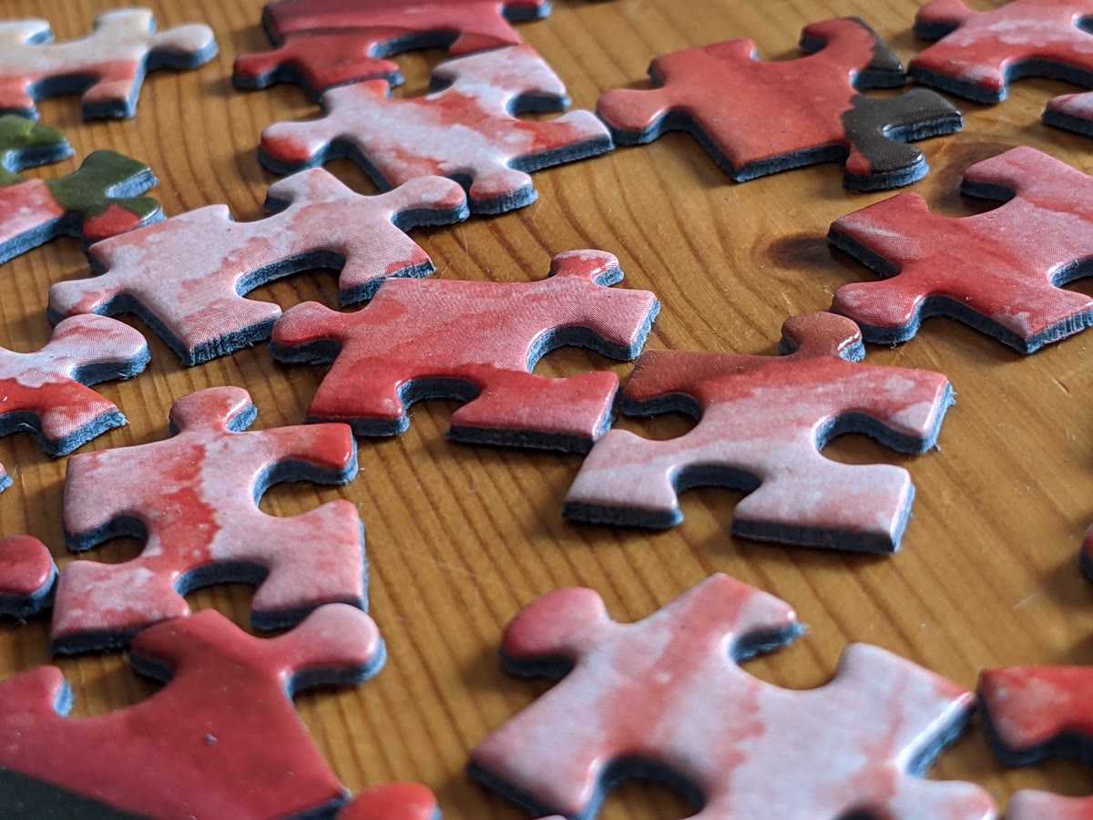 Red jigsaw puzzle pieces scattered on a surface, representing how GhostSplice splits one malicious instruction into harmless fragments