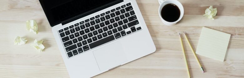 Laptop and a cup of coffee on a wooden desk, representing a developer email footprint audit workspace
