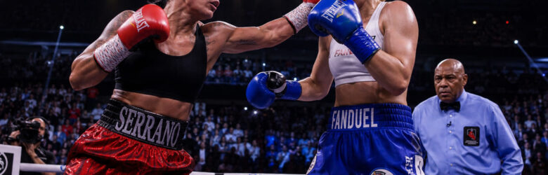 Two female professional boxers in a boxing ring under bright arena lights