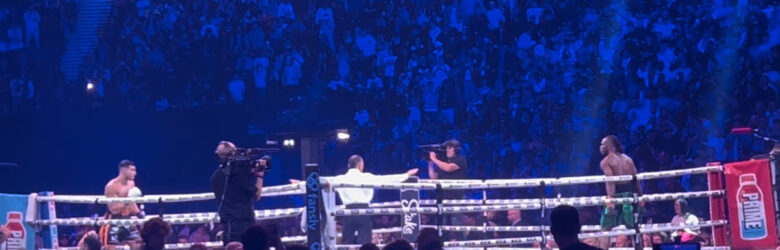 Two boxers competing in a professional boxing match under arena lights