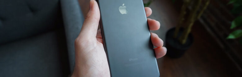 A hand holding a smartphone — the device through which AI voice and text scams arrive
