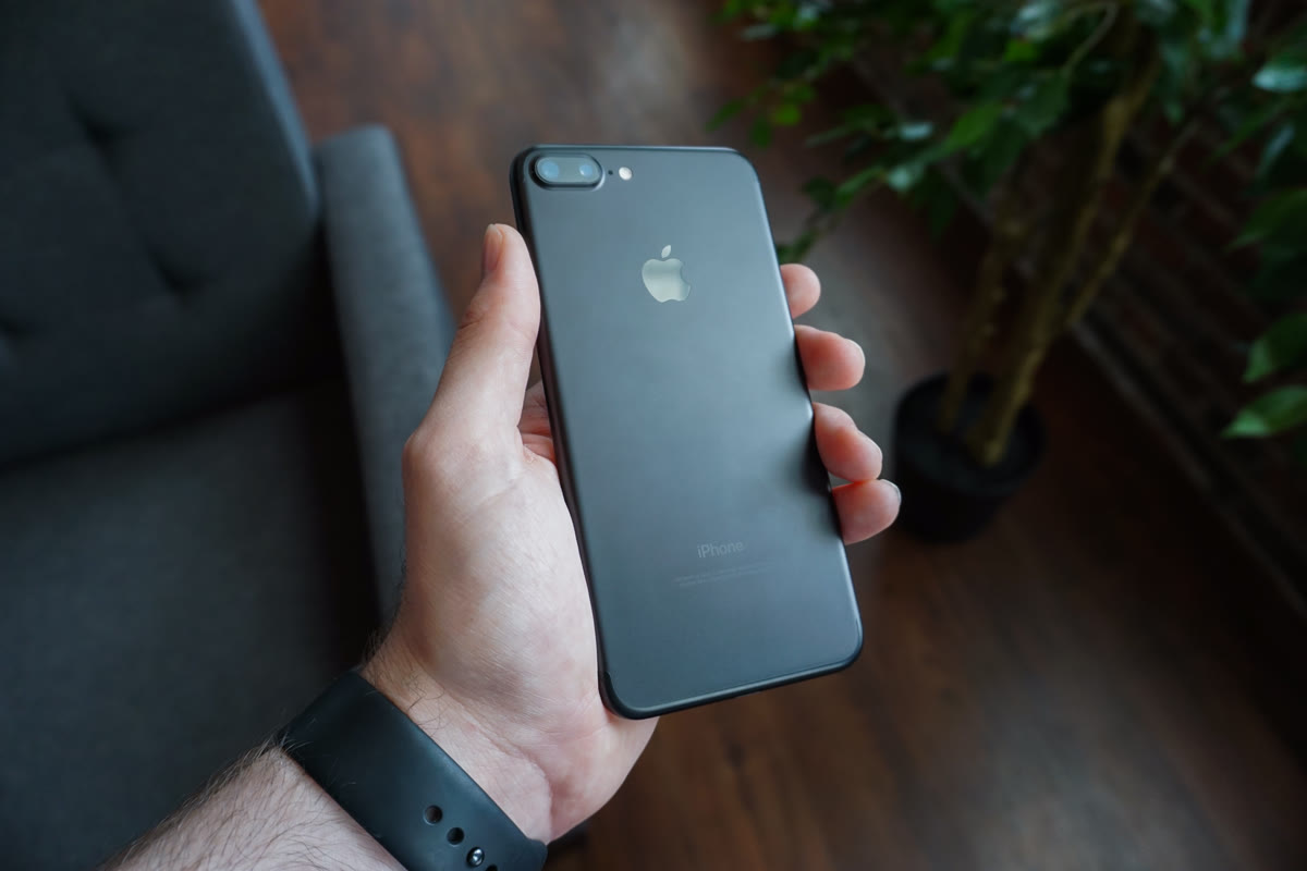 A hand holding a smartphone — the device through which AI voice and text scams arrive
