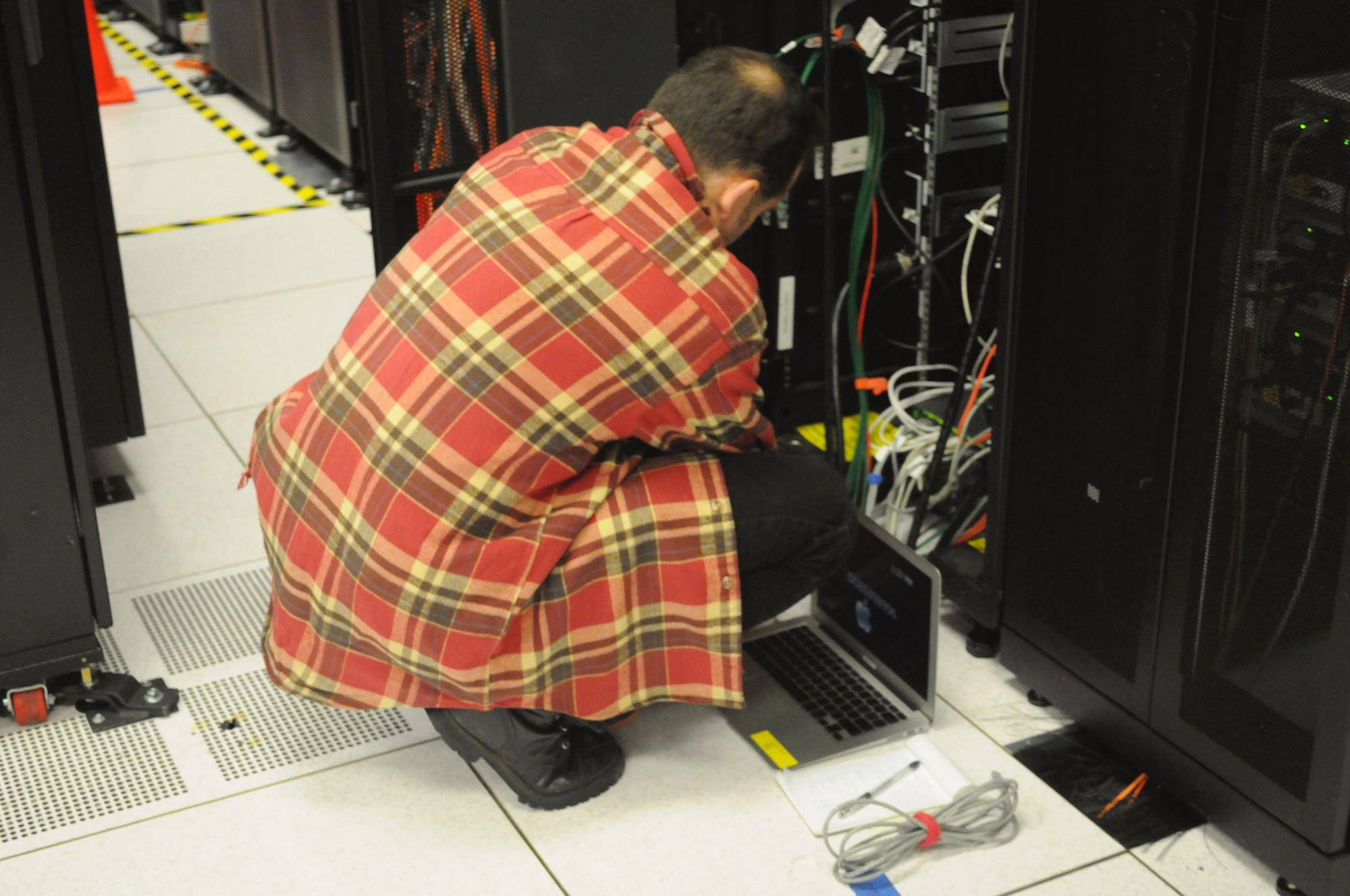 Technician working on a server rack at a data center, representing the AI infrastructure behind model deployment