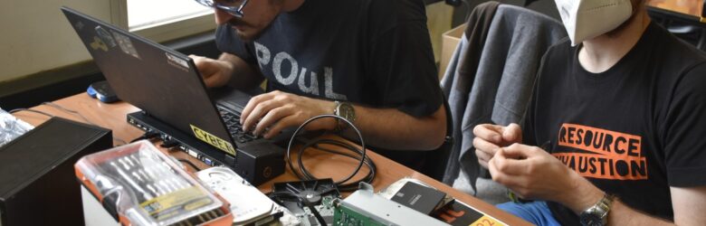 Hackers working on a Linux laptop with computer disks and repair kits at Hackers on Milan 2022, representing the hands-on security research that AI security platforms like HiddenLayer build on