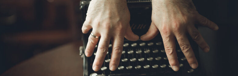Close-up of hands typing on an old typewriter, a visual metaphor for human-written text and AI text detection