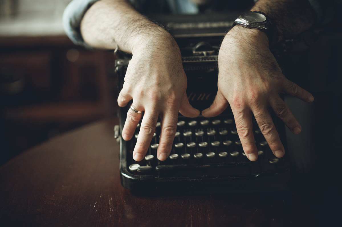 Close-up of hands typing on an old typewriter, a metaphor for detecting human vs AI text