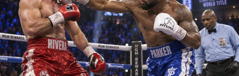 Two boxers trading punches in a boxing ring under bright arena lights