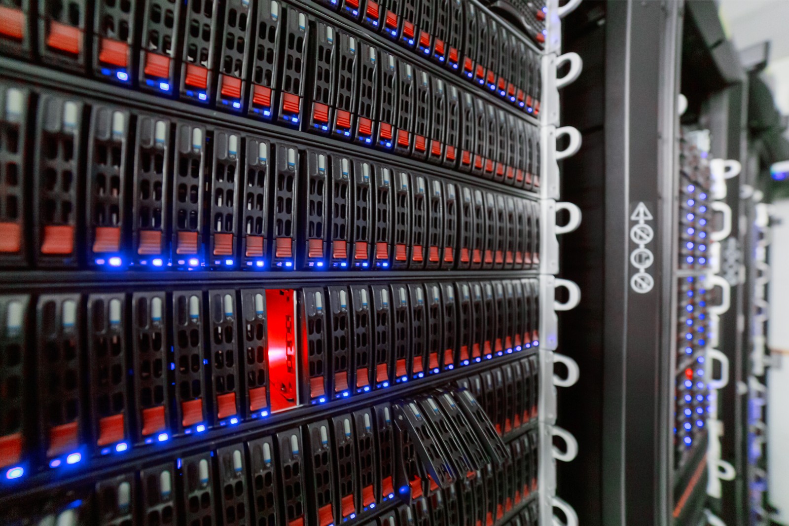 Rows of server racks with colourful network cabling inside a data center