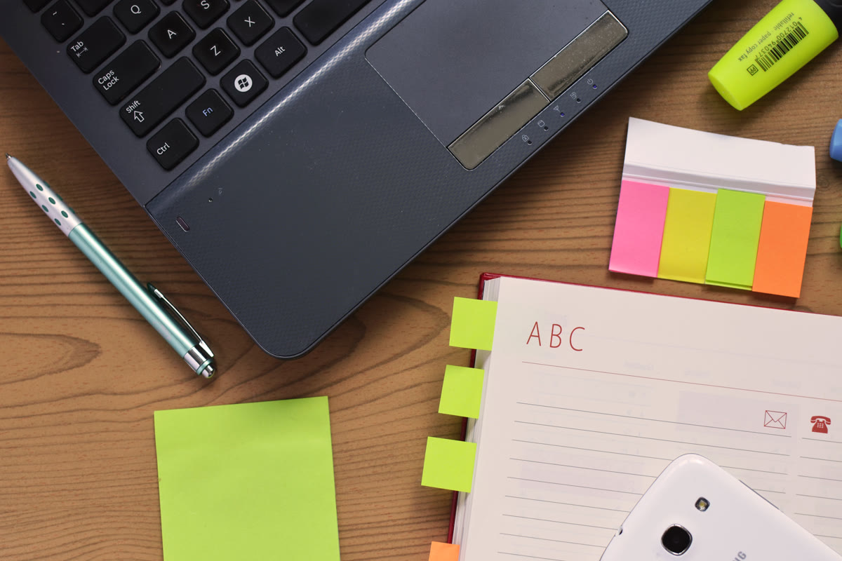 A workspace desk with a laptop, notebook, and pen